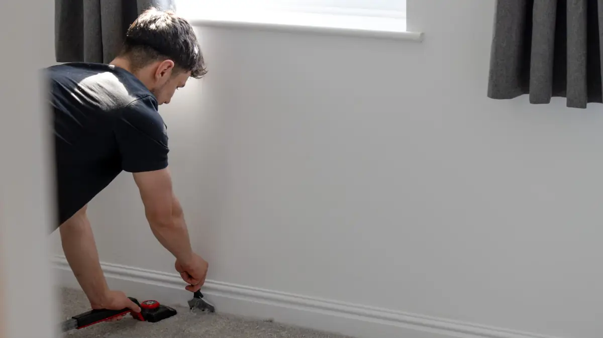 Stretching grey bedroom carpet tight to the skirting with a carpet stretcher in Warwickshire